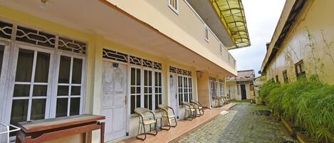 A building with a tiled courtyard, multiple doors with glass panels, and outdoor seating.