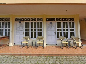 A building with two doors, numbered 102 and 103, and four chairs in front. - OYO 3722 Hotel Mutiara (Purwokerto)