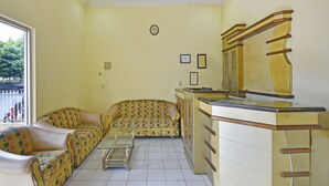 Een woonkamer met een zithoek, een glazen salontafel en een kast met spiegel.