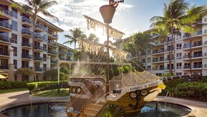 Un área de piscina con un bote tiki, una torre de salvavidas y una palmera.