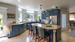 Une cuisine moderne avec des meubles de couleur bleu foncé, un plan de travail en granit et un îlot central doté de tabourets de bar.