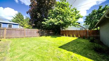 A backyard with a wooden fence, a large tree, and a lawn.