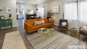 Una sala moderna con sofá, sillones, una mesa de centro y un comedor al fondo.