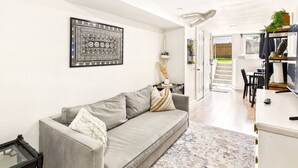 Un salón moderno con un sofá gris, una alfombra estampada y una obra de arte enmarcada en la pared.