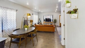 Una sala de estar moderna con una mesa de comedor de madera, un sofá y un televisor.