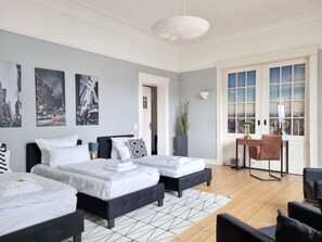 A modern hotel room with two beds, a desk, and a view of the city.