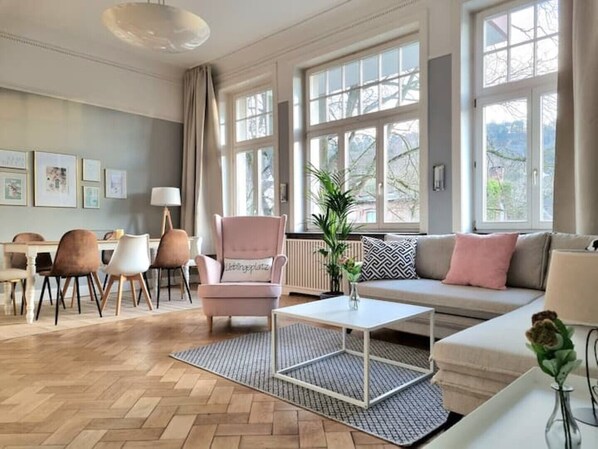 A modern living room with a sofa, armchair, coffee table, and dining area.
