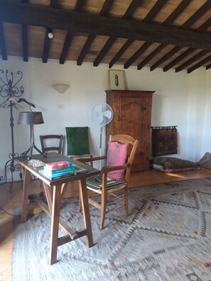 Une pièce chaleureuse avec une table en bois, des chaises, un ventilateur, un meuble et un tapis à motifs.