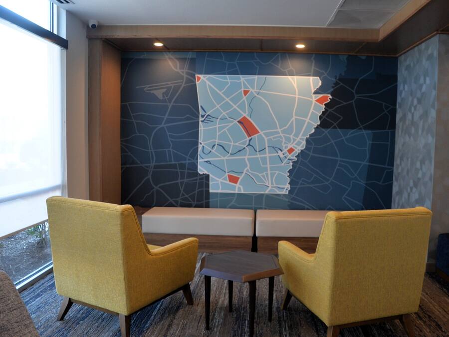 A conference room with two yellow chairs, a small table, and a large abstract wall art piece.