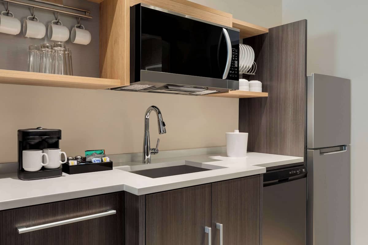 A modern kitchen with a built-in microwave, stainless steel appliances, a coffee maker, and a dishwasher.