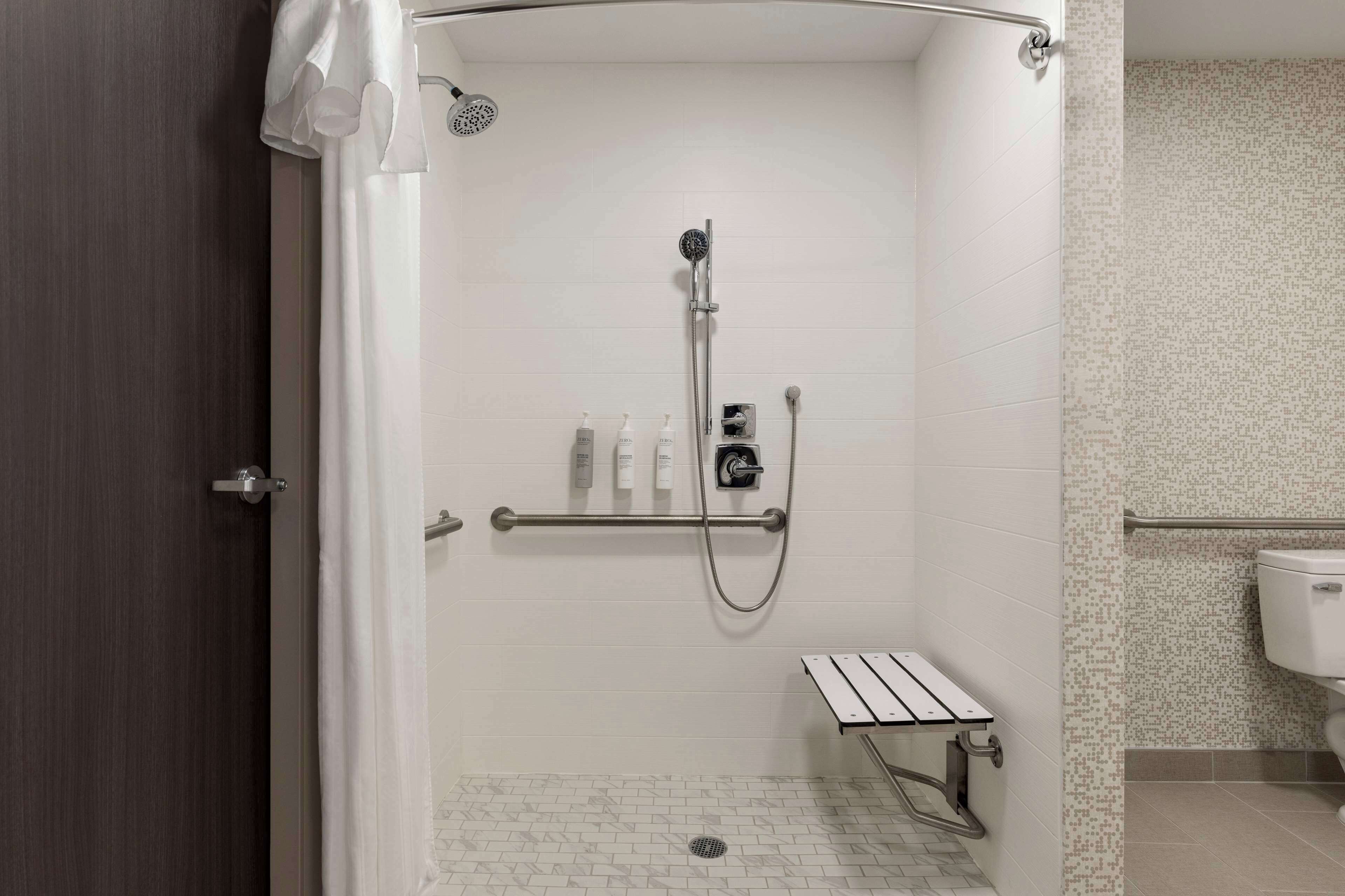 A shower area with a handheld showerhead, a handheld showerhead, and a handheld showerhead.