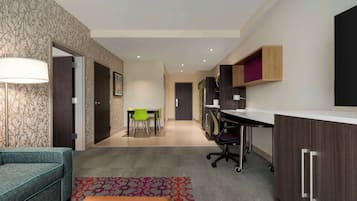Een moderne hotelkamer met een bank, bureau, stoel en een klein eettafeltje.