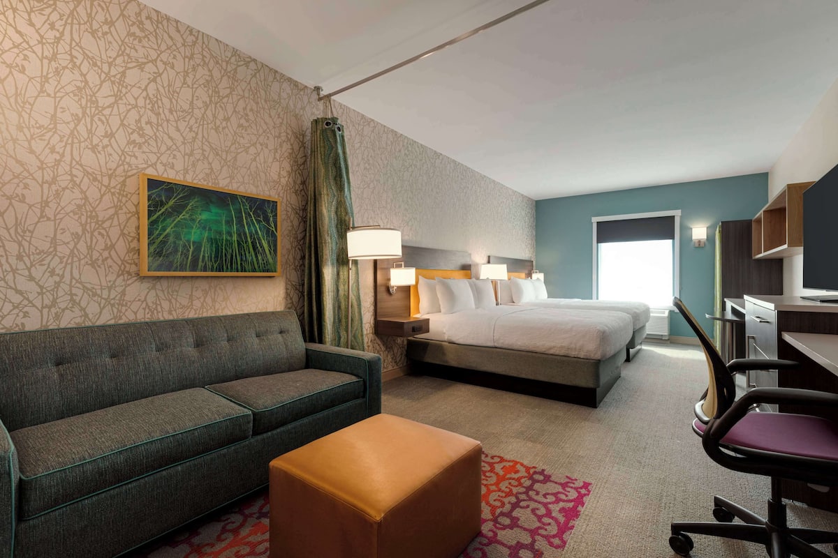 A hotel room with a bed, a sofa, a desk, and a chair.