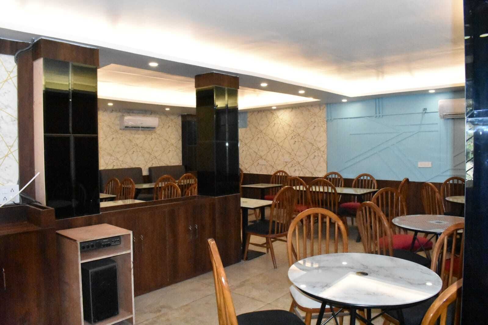 A restaurant with wooden chairs and tables, a counter area, and a patterned wall.