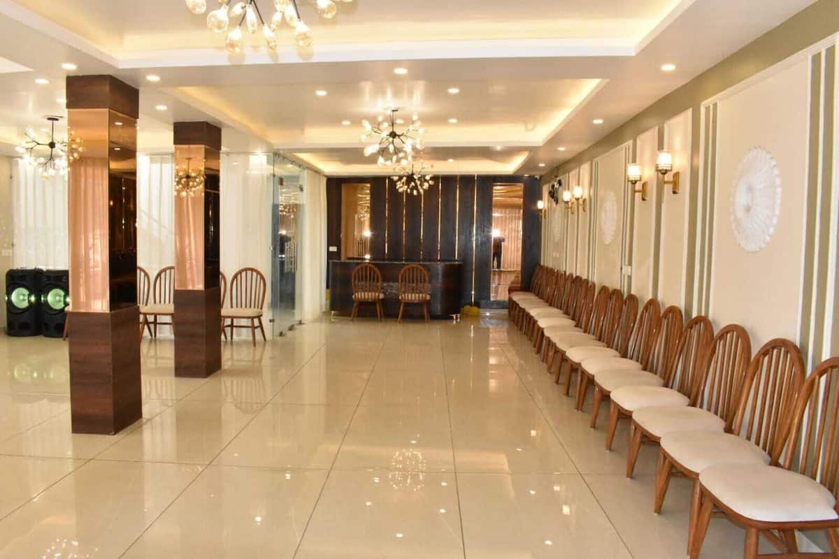 Un vestíbulo de hotel con una hilera larga de sillas de madera, un mostrador de recepción y una araña.