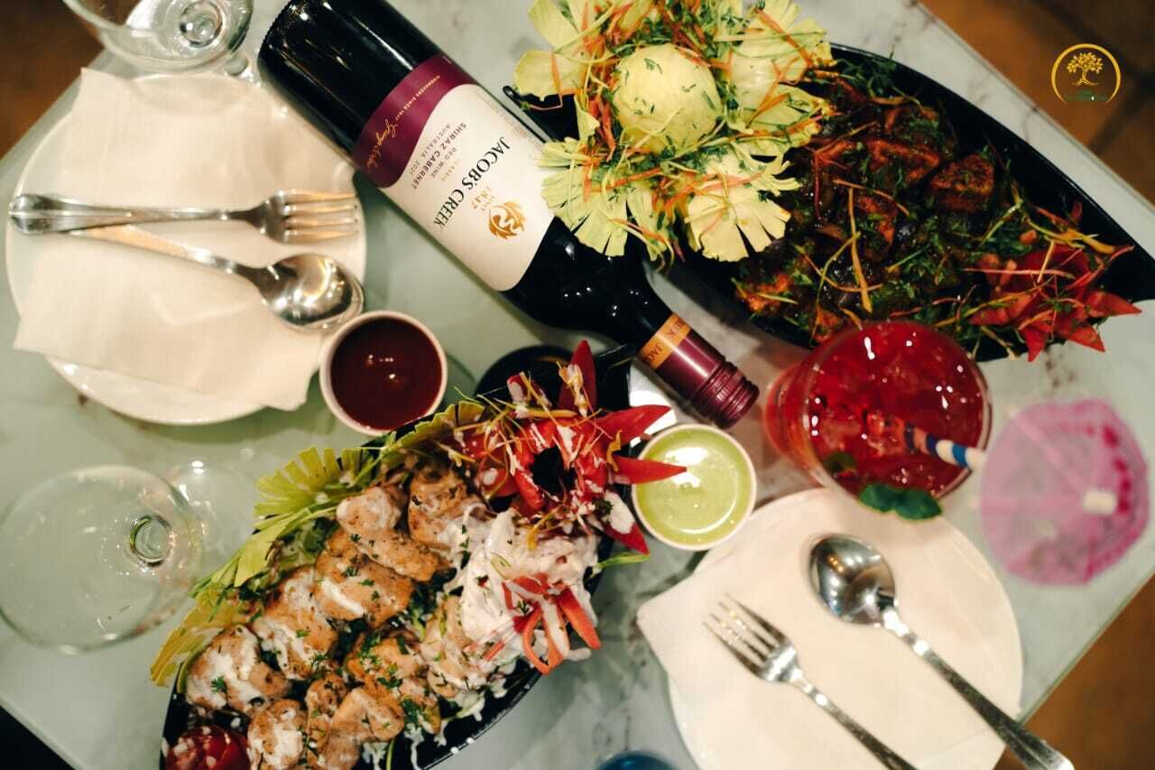A dining table with various dishes, a bottle of wine, and cutlery.