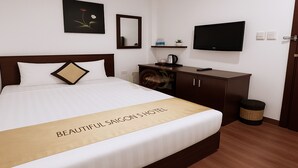 A hotel room with a bed, a TV, a mirror, a shelf with toiletries, and a trash bin. - Beautiful Saigon Hotel (Ho Chi Minh City)
