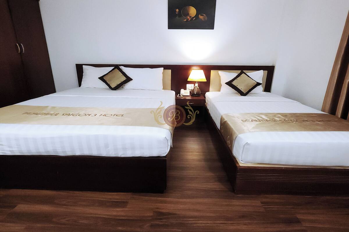 A hotel room with two beds, a nightstand with a lamp, and a framed picture on the wall.