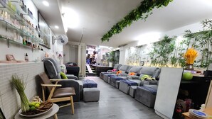 A modern living room with a sofa, a chair, and a small table with a plant. There are shelves with various items on the wall, and a fan on the ceiling. - Beautiful Saigon Hotel (Ho Chi Minh City)
