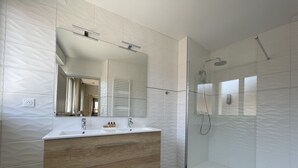 Ein modernes Badezimmer mit einem Holzlager, einer Duschkabine aus Glas und einem großen Spiegel.