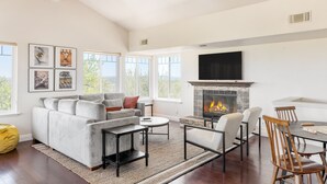A spacious living room with a fireplace, a sofa, a coffee table, and a dining area with chairs.