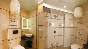 A bathroom with two toilets, a sink, a mirror, and a shower area. - Limewood Stay - Cyber Hub (Gurugram)