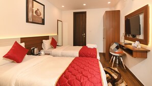 A hotel room with two beds, a desk, a chair, a TV, and a mirror. - Limewood Stay - Cyber Hub (Gurugram)