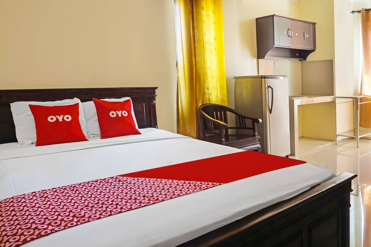 Habitación de hotel con una cama bien hecha, un escritorio con silla, un armario y una televisión.