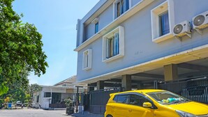 Um edifício moderno de dois andares, com aparelhos de ar condicionado na parede externa, portão e um carro amarelo estacionado na frente.