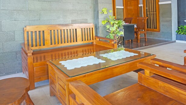 Um conjunto de banco e mesa de madeira numa sala com parede de pedra e planta em vaso.