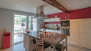 A modern kitchen with a central island, stainless steel appliances, and a red accent wall. - Country house in a village with character (Saint-Galmier)