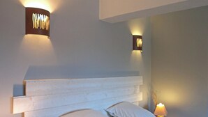 A bedroom with a bed, pillows, a nightstand, a lamp, and a suitcase. - Country house in a village with character (Saint-Galmier)