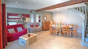 A spacious living area with a dining table, red sofa, and a kitchen in the background. - Country house in a village with character (Saint-Galmier)