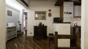A compact kitchen with wooden flooring, a dark wooden cabinet, a small table, and a television on a stand. - Dupr 5 (Milan)
