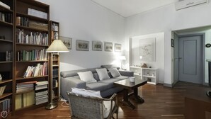 A living room with a grey sofa, a bookshelf, a lamp, and framed pictures on the wall. - Dupr 5 (Milan)
