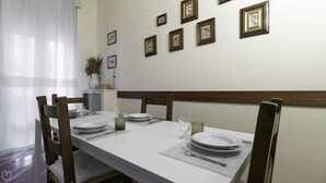 A dining area with a white table set for four, wooden chairs, and framed pictures on the wall. - Dupr 5 (Milan)