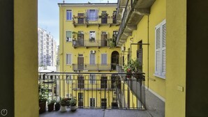 A yellow building with multiple balconies, a visible staircase, and potted plants on the balcony. - Italianway Comfort - Bligny 19A D Bologna (Milan)