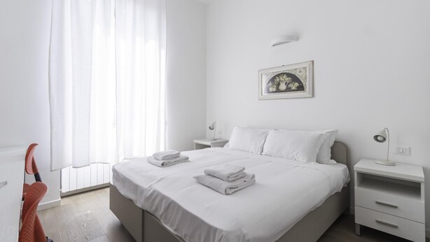 A neatly made bed with white linens and towels, a bedside lamp, and a framed picture on the wall. - Italianway Comfort - Bligny 19A D Bologna (Milan)