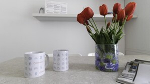 A kitchen counter with a vase of red tulips, two white mugs with icons, and a menu on the right. - Italianway Comfort - Bligny 19A D Bologna (Milan)