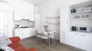 A modern kitchen with white cabinets, a dining table with chairs, a red sofa, and a white bookshelf with a 'Welcome' sign. - Italianway Comfort - Bligny 19A D Bologna (Milan)