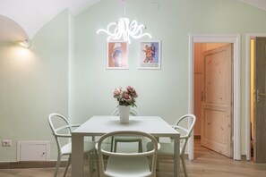 A dining area with a white table, four chairs, a vase with flowers, and two framed pictures on the wall. - Ramaglianti Apartment (Florence)