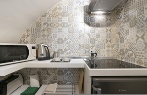 Una cucina con forno a microonde, macchina del caffè e bollitore sul piano di lavoro.