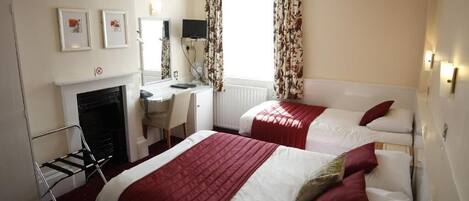 Une chambre d’hôtel avec deux lits, un bureau, une chaise, une cheminée et un téléviseur.