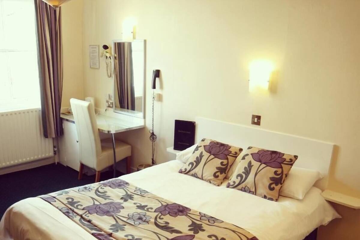 Une chambre d’hôtel avec un lit, un bureau et une chaise.