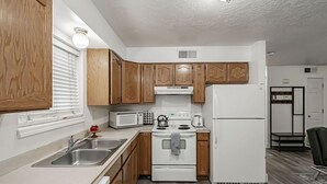 Una cocina compacta con armarios de madera, estufa blanca, microondas y refrigerador.