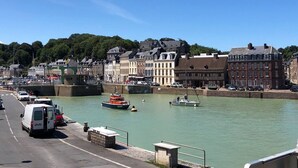 Eine Stadt am Flussufer mit historischen Gebäuden, einer Brücke und Booten auf dem Wasser.
