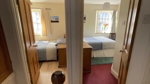 A hallway leading to two bedrooms with wooden floors, a red carpet, and a window with curtains. - Robinson’s Cottage in Cockermouth quiet and central (Cockermouth)
