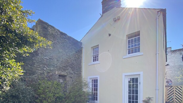 A two-story building with a stone wall on one side and a paved courtyard. - Robinson’s Cottage in Cockermouth quiet and central (Cockermouth)