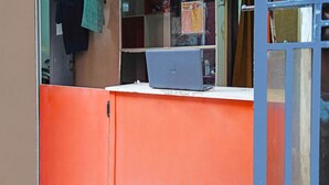 A laptop on a white counter with a red cabinet behind it. - SPOT ON 91783 Urban Syariah ResidenceNearGOR Pandawa Lima (Bandung)