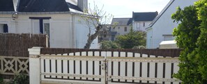 Ein begrenzter Eingangsbereich mit schmiedeeisernem Tor und einer weißen Mauer mit Fenster und Tür.